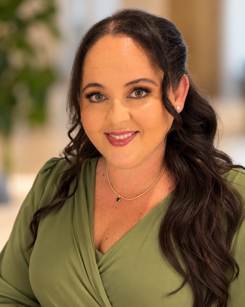 Professional portrait of Lorinda Gonzalez-Santana, Founder and Principal Consultant of Remy's Consulting, smiling warmly in a green dress against a softly blurred background